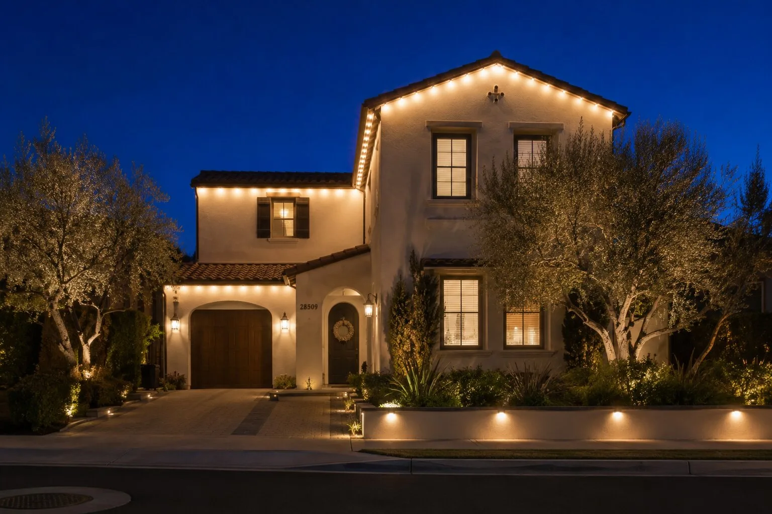 Warm-white permanent LED lights along the eaves of a Spanish-style home at dusk